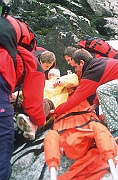 Ratownicy TOPR pakuja rannego turyste do noszy, przygotowanie do transportu.
